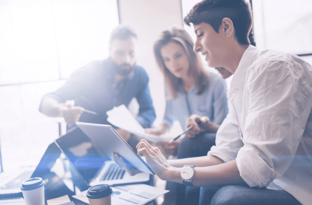 three people looking at documents and laptops